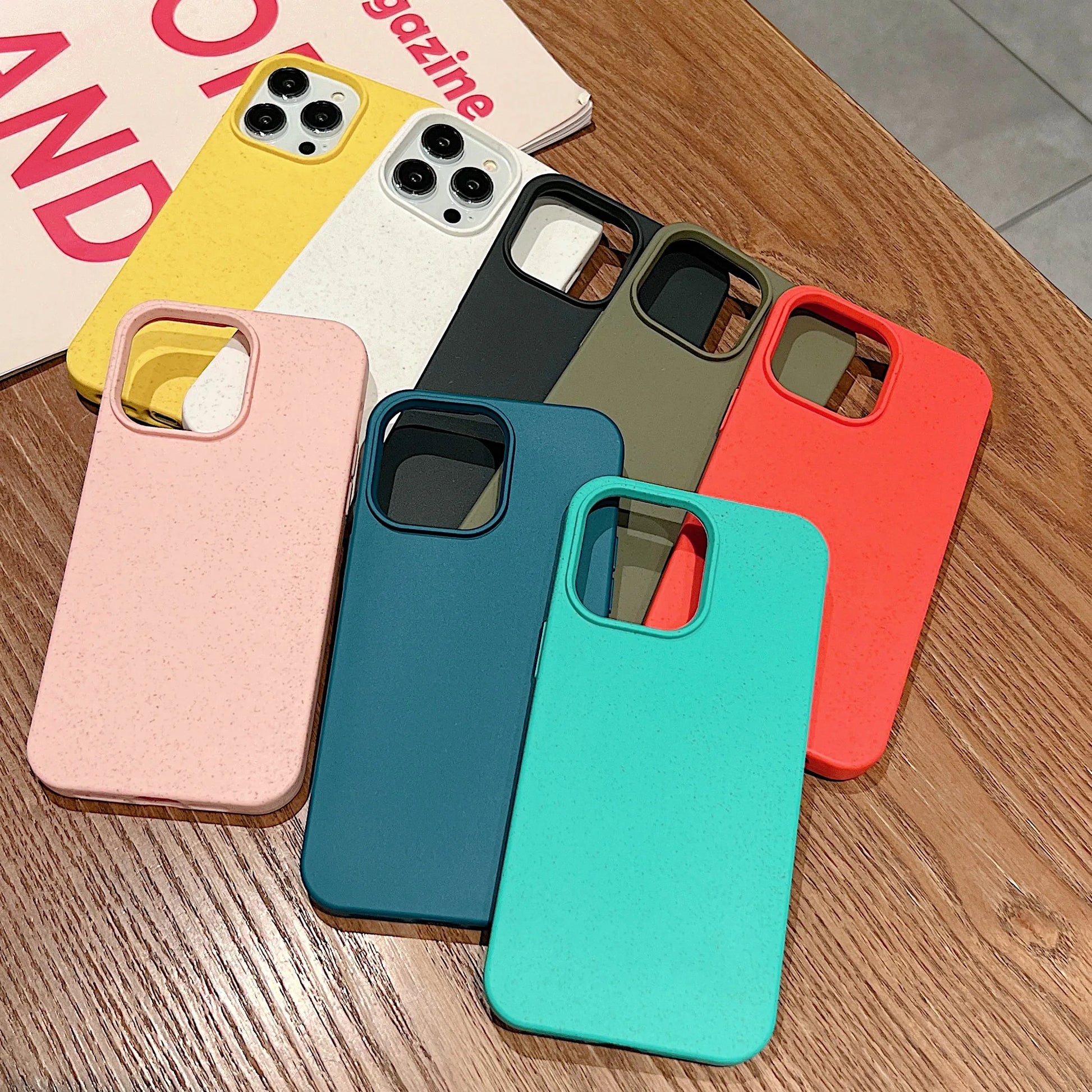 Sieben umweltfreundliche iPhone Hüllen in verschiedenen Farben aus nachhaltigem Material auf Holztisch